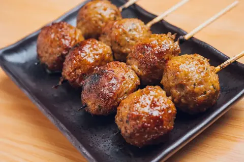 焼鳥どん町田店の名物、甘辛ダレがかかったつくね串が複数本並んで盛り付けられた写真