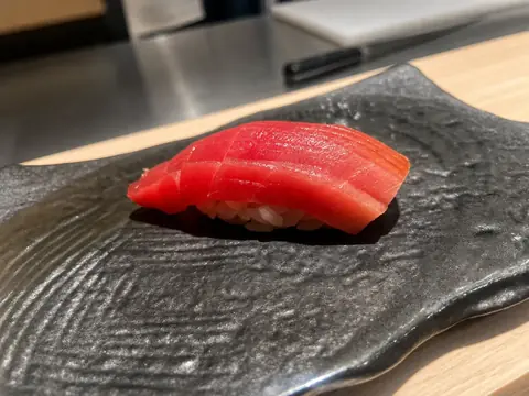 鮨とも縁の黒い器に盛られたまぐろの握り寿司の写真