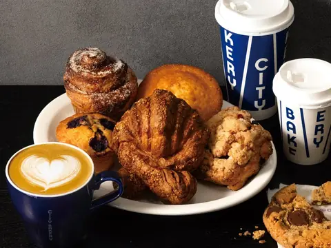 THE CITY BAKERYのプレッツェルクロワッサンやマフィンなどのパンとカフェラテが並んだ写真