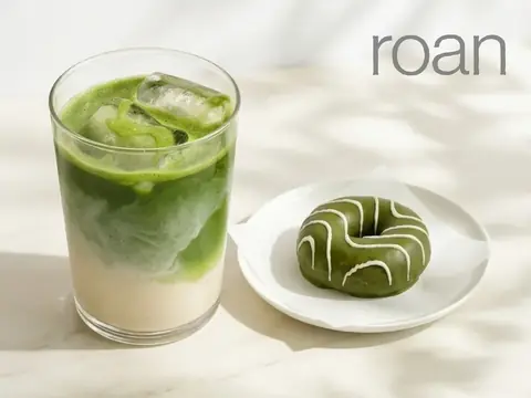 roan(ロアン)の氷入り抹茶ラテと白いアイシングがかかった抹茶ドーナツが白い皿に並んだ写真
