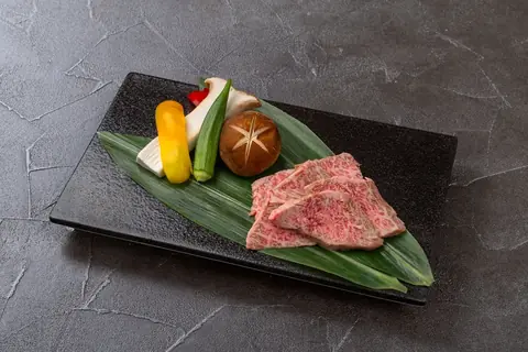 いだ天別邸 高山でこなる店の牛肉と彩り野菜を使った陶板焼きを笹の葉に盛り付けた写真