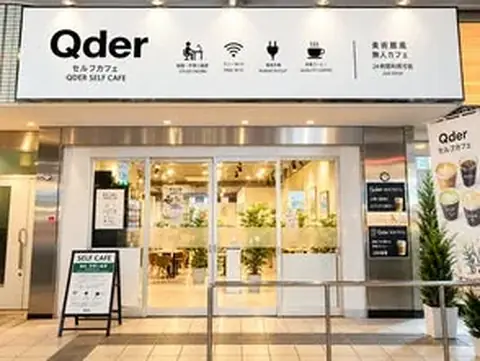 Qderセルフカフェ千代田駅前店の外観、自動ドアと看板、植栽が並ぶ店舗入口の写真