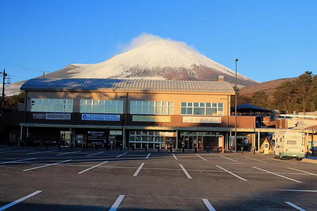 道の駅すばしり（静岡県小山町）の、雪をかぶった高い山を背にした建物と空いた駐車場の写真