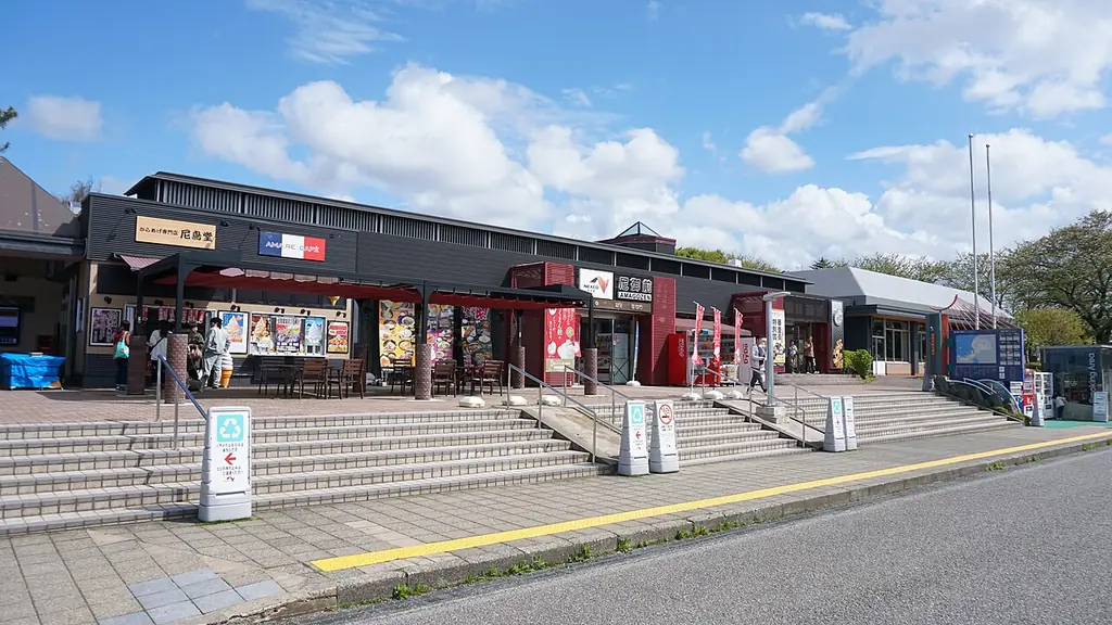 尼御前サービスエリアの、店が並ぶ黒い屋根の建物と、そこへ上る広い階段と手すりの写真