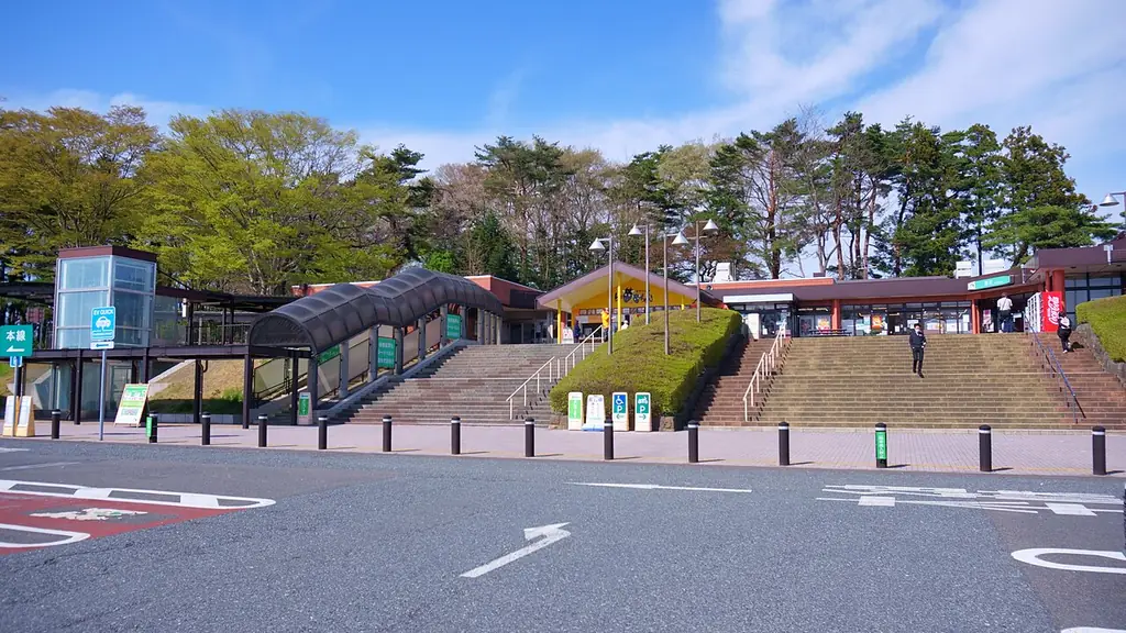 前沢サービスエリア（下り）の、建物へ上る広い階段とガラスの通路、手前の車道と木々の写真