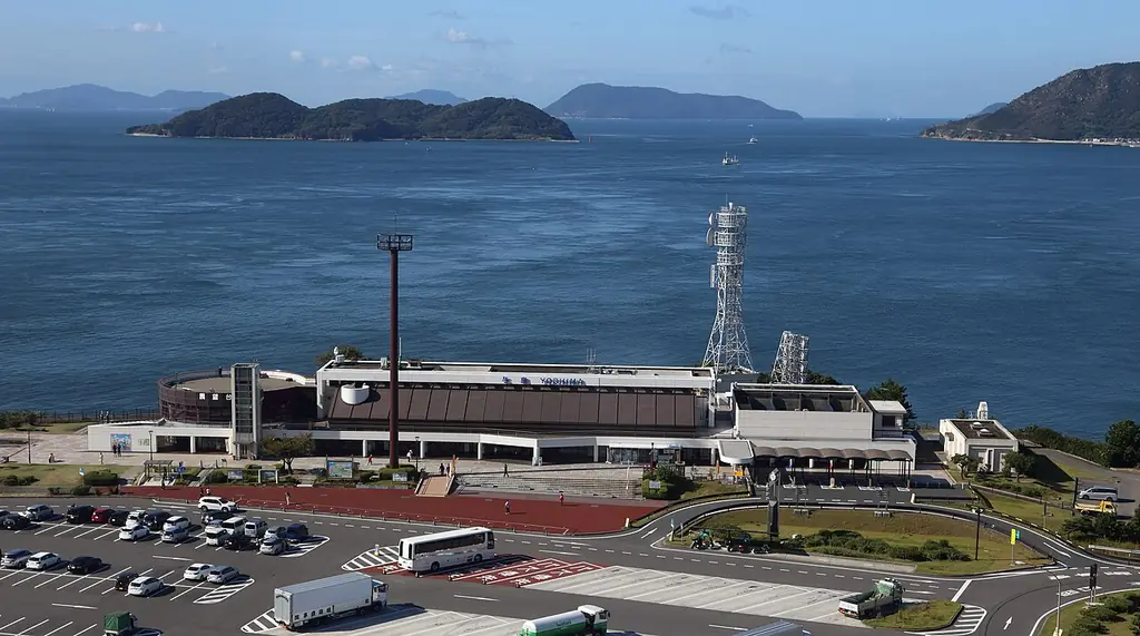 与島パーキングエリアを高い所から見た、建物と広い駐車場、うしろに広がる海と島々の写真