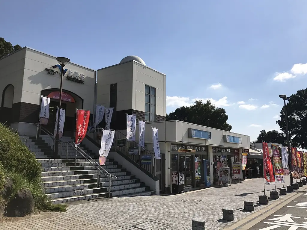 北熊本サービスエリアの、建物へ上る石の階段と並ぶのぼり、その横で店が並ぶ建物の写真