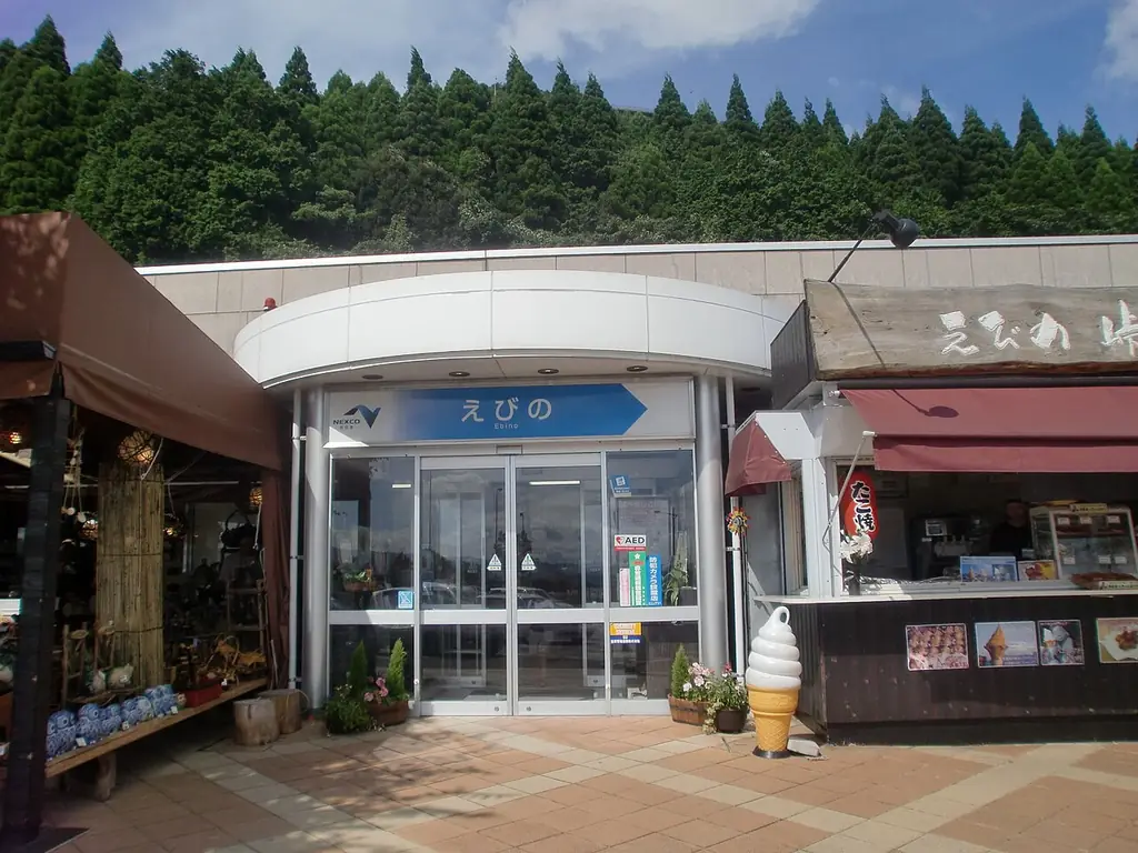 えびのパーキングエリアの、「えびの」の看板が付いたガラスの入口と、両側の店先の写真