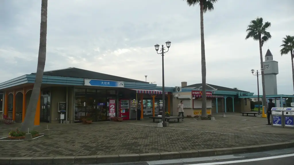 大村湾パーキングエリアの、青い屋根の建物とヤシの木、灯台のような白い塔と前の広場の写真