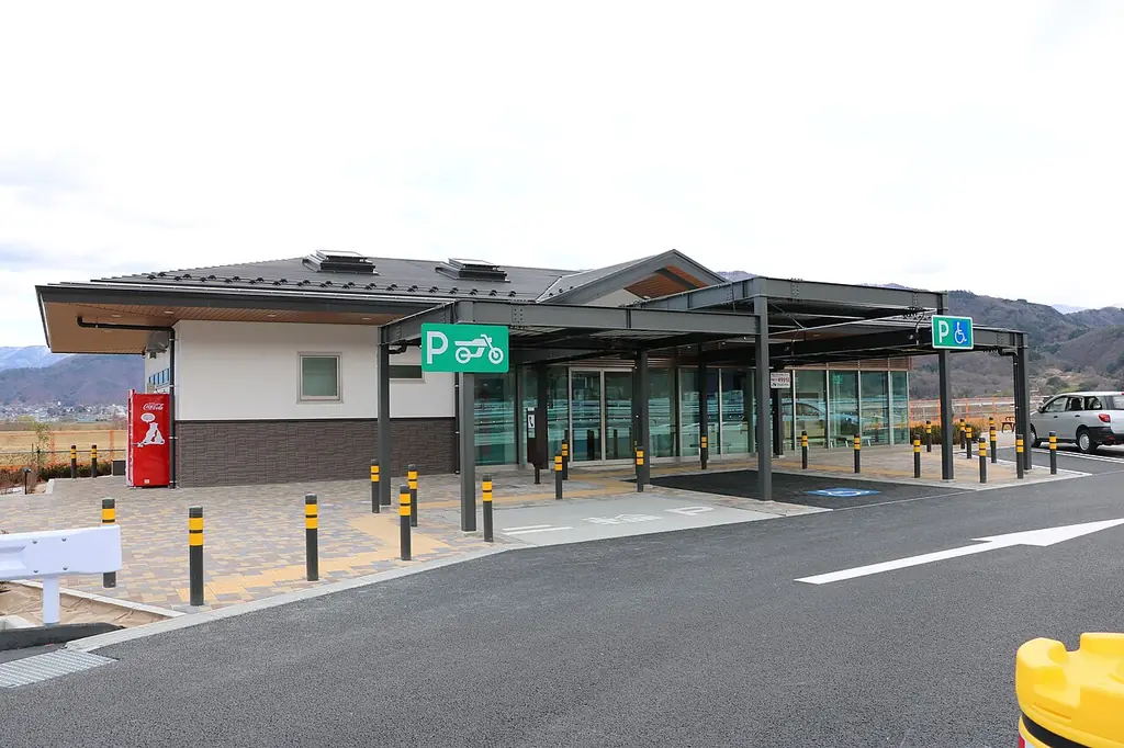 増穂パーキングエリアの、P看板の付いた屋根の通路と白い壁の建物、前の歩道と車止めの写真