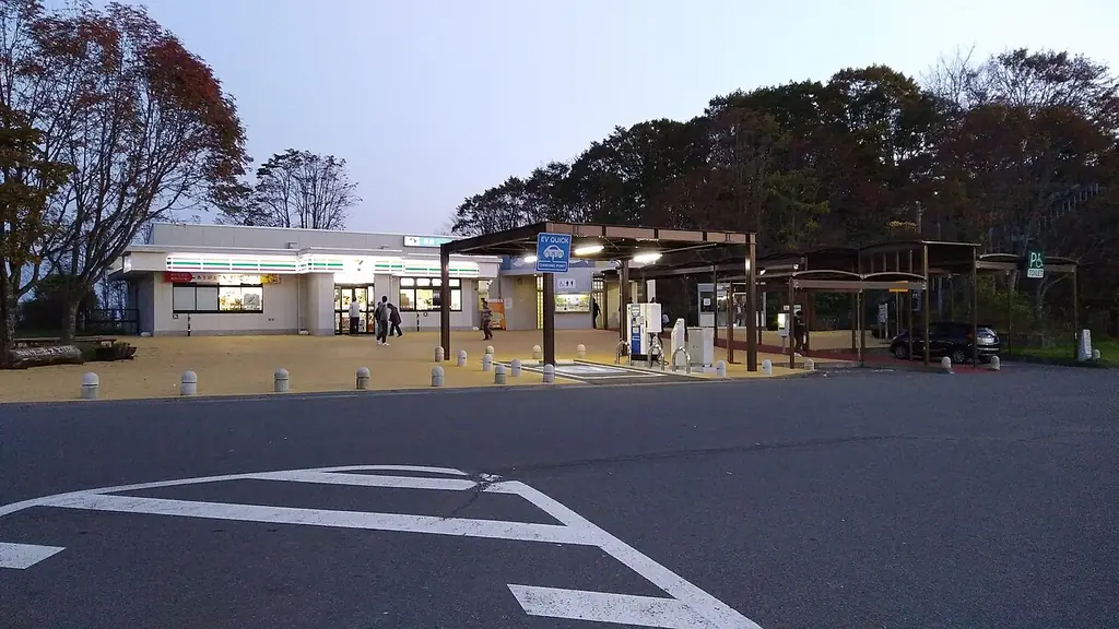 樽前サービスエリア（上り）の、白い建物と屋根の付いた通路、白線の引かれた広い駐車場と木々の写真