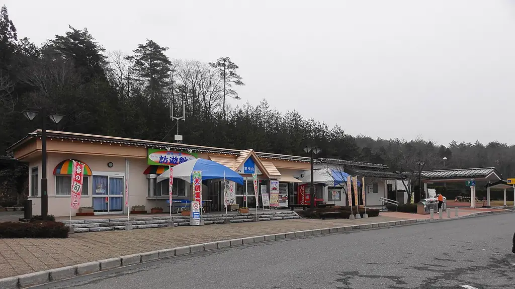 寒曳山パーキングエリアの、屋根の付いた通路と平屋の建物、パラソルと前の駐車場、うしろの林の写真