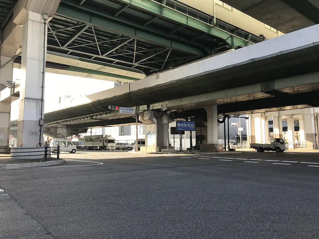 弁天町駅前交差点の、上下2段に重なる高速道路の高架と、信号機と「弁天町駅前」の青い案内板の写真