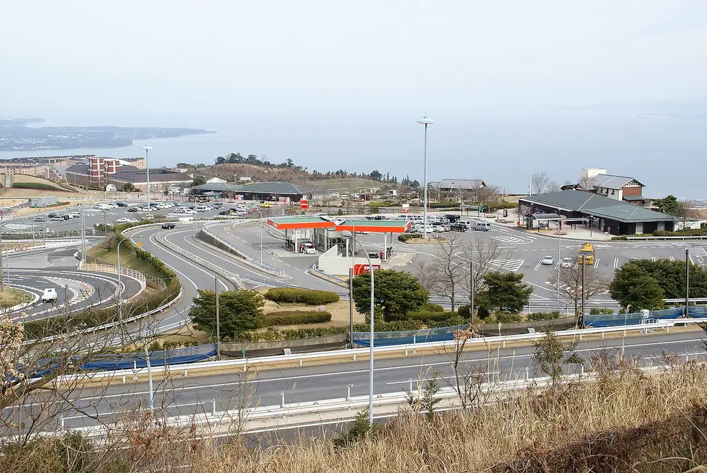 別府湾サービスエリアを高い所から見た、建物と駐車場、手前の道路と奥に広がる海の写真