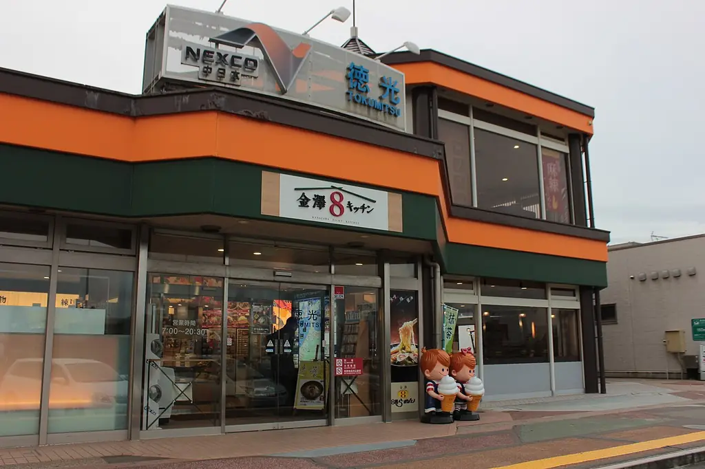 徳光パーキングエリアの、「徳光」の看板が付いたオレンジと緑の建物と、「金沢8番らーめん」の看板が見える入口の写真