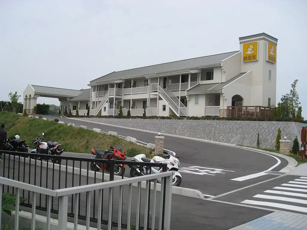 壇之浦パーキングエリアの、白い2階建ての建物と黄色い看板の塔、手前のバイクと坂道の写真
