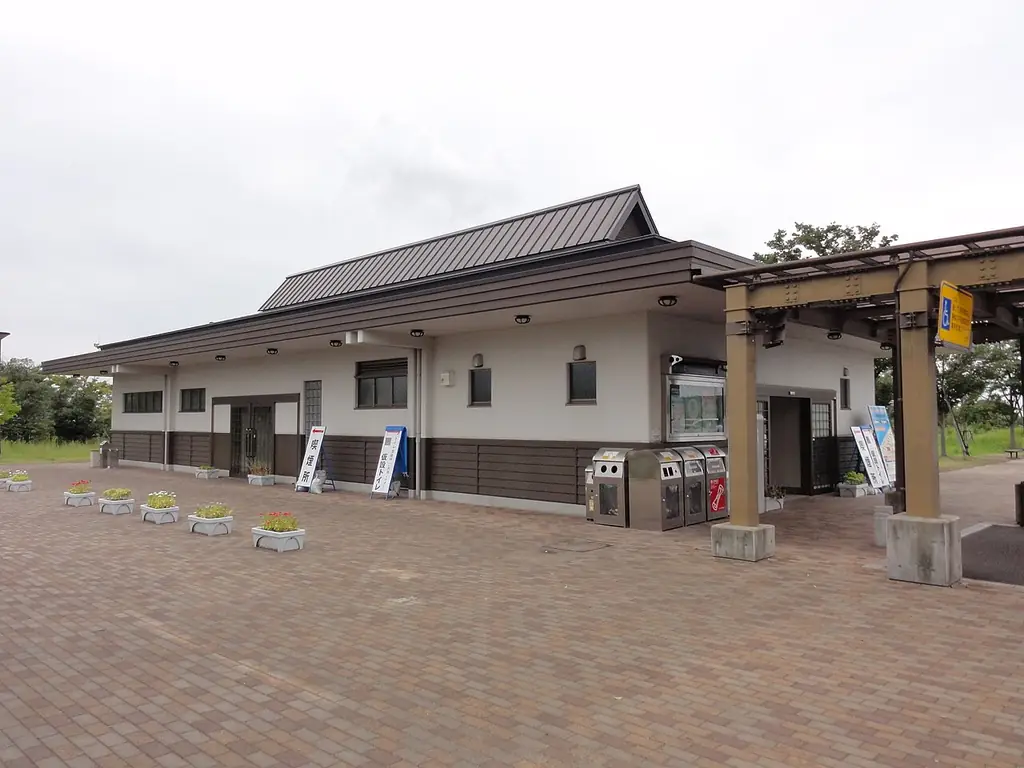 豊栄サービスエリアの、瓦屋根の平屋の建物と木の屋根の通路、手前のレンガ色の広場の写真