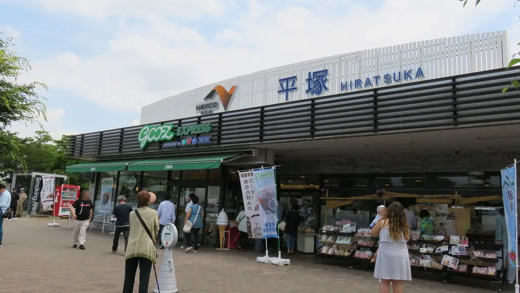 平塚パーキングエリアの、「平塚 HIRATSUKA」の看板が付いた建物と、店先に並ぶ品物と人たちの写真