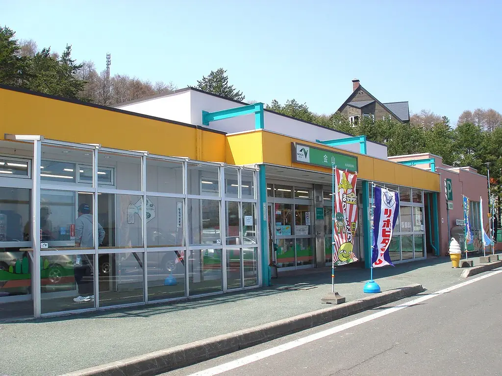 金山パーキングエリア（小樽方面）の、黄色と白の壁でガラス窓が並ぶ建物と、店先ののぼりの写真
