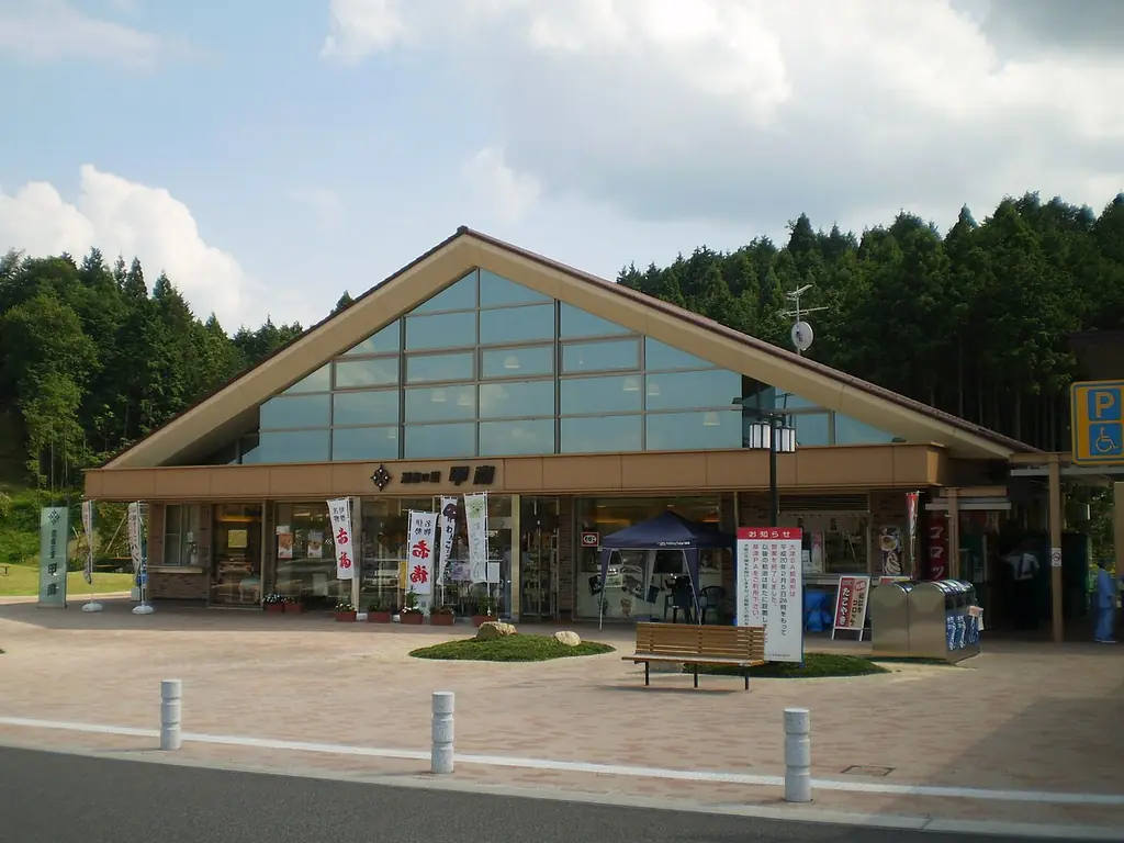 甲南パーキングエリアの、三角の大きな屋根とガラスの壁の建物と、前の広場のベンチの写真