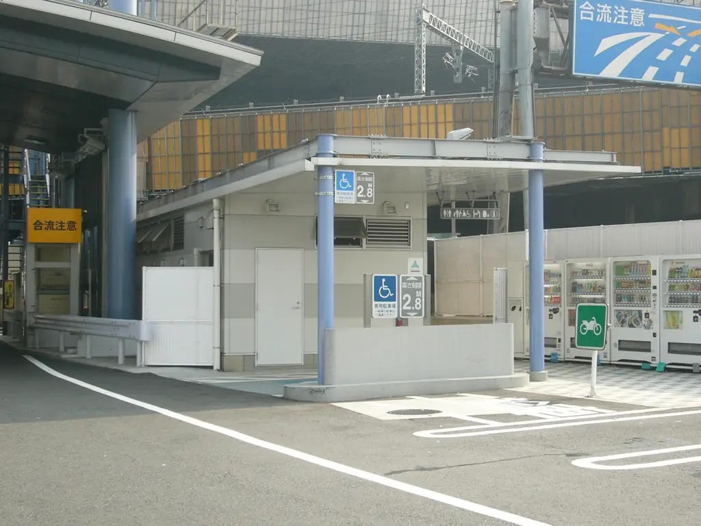 大井パーキングエリアの、高架の下にある白い休憩所の建物と自販機、手前の白線の引かれた路面の写真