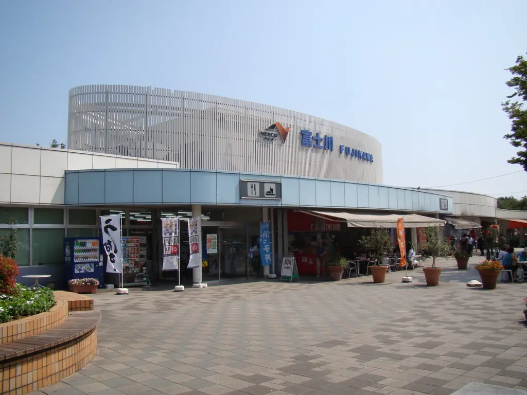 富士川サービスエリア（下り）の、「富士川」の看板が付いた丸い外壁の建物と、店の前の広場と植え込みの写真