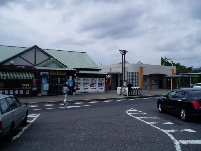 吉備湯浅パーキングエリア（上り）の、緑色の屋根の売店と自動販売機が並ぶ建物、手前の駐車場に止まる車の写真