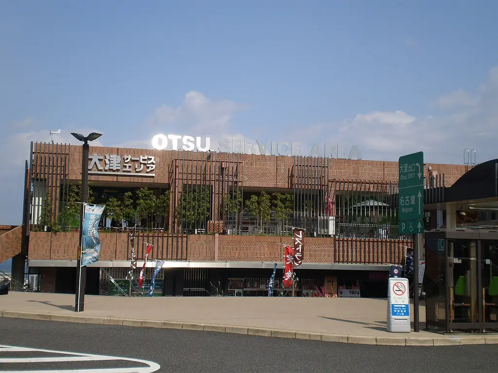 大津サービスエリアの、「OTSU」の文字と木の格子が付いた建物と、前の歩道と案内標識の写真