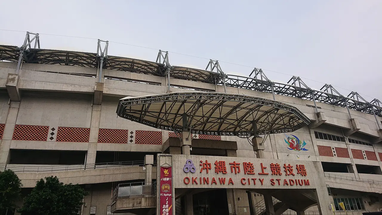 沖縄市陸上競技場(会場)の入口で、スタンドの外壁の「沖縄市陸上競技場」の文字と、入口の上の円い屋根の写真