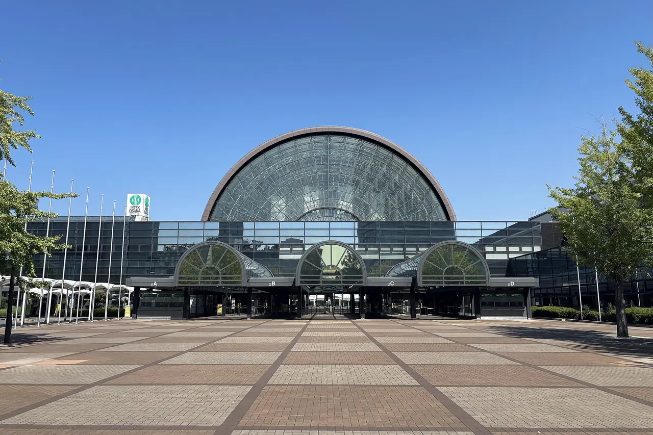 インテックス大阪（会場）の、半円形のガラス屋根がかかった入口の建物と、手前に広がるれんが敷きの広場の写真