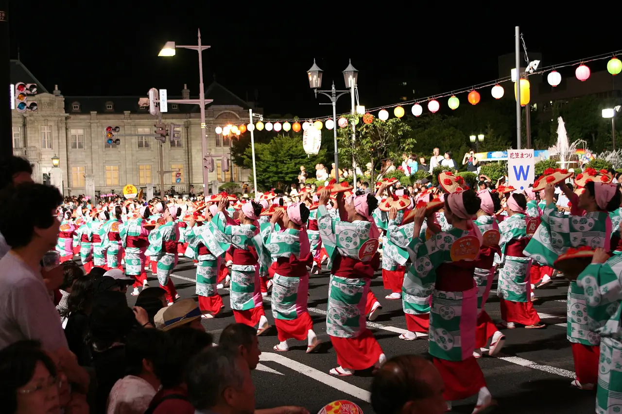 山形花笠まつりで、提灯が連なる夜の通りを、花笠を持った浴衣の踊り手たちが列になって踊る様子の写真