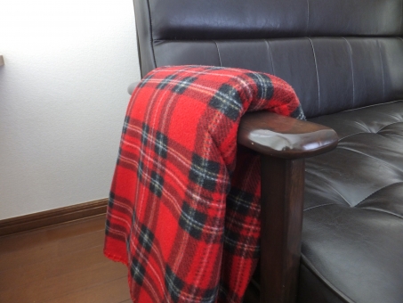 ソファの肘掛けに掛けた赤いチェックのひざ掛け