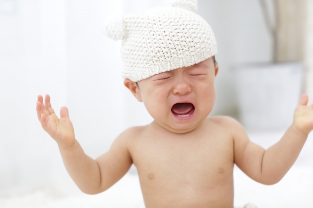 白い帽子をかぶって泣いている赤ちゃん