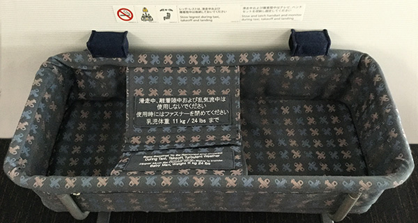 機内の壁に取り付けられた紺色のバシネット