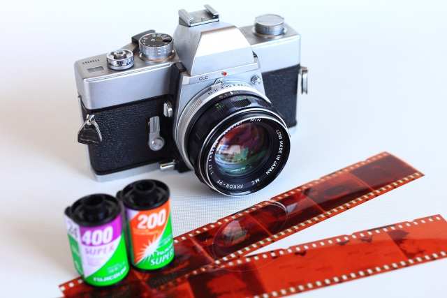 銀色のフィルム一眼レフと35mmフィルム2本と現像したネガ