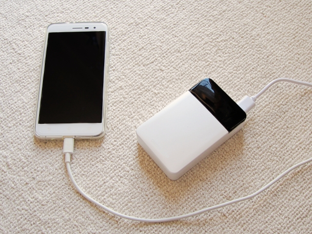 白いスマートフォンとモバイルバッテリーをケーブルでつないだ写真