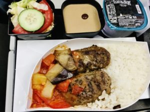 機内食のトレー。ごはんと煮込み料理とサラダとデザート