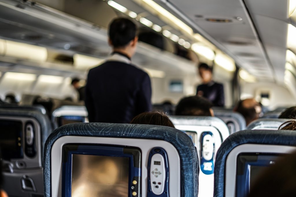 通路を歩く客室乗務員と機内の座席の背もたれ