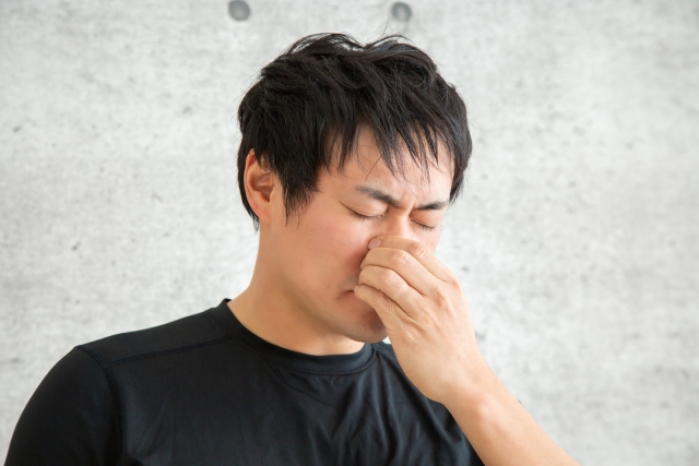 鼻のつけ根を押さえて顔をしかめる男性