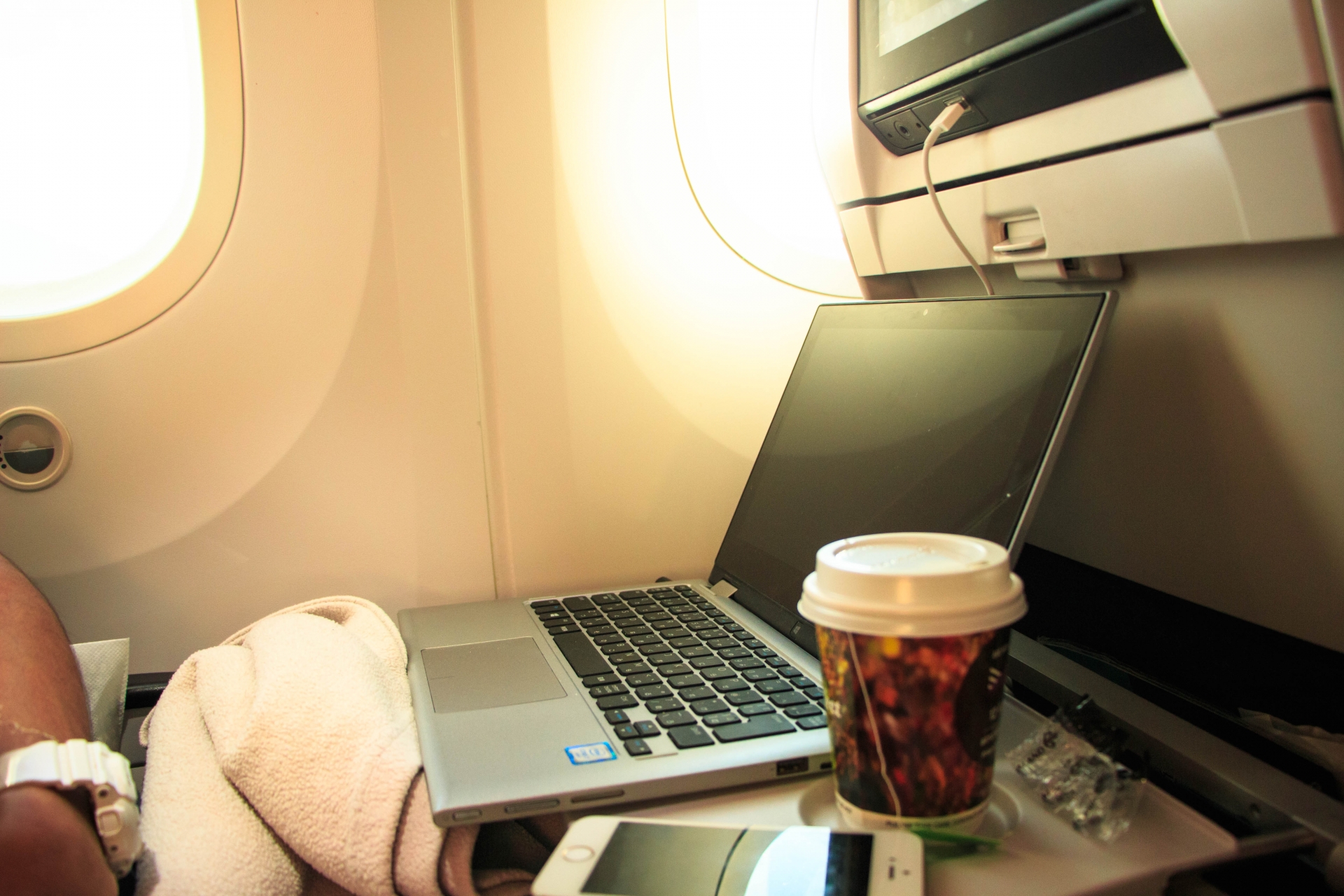 機内のテーブルでノートパソコンとコーヒーを置いたところ