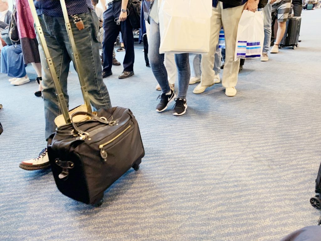 空港でキャスター付きのかばんを引く人の足元
