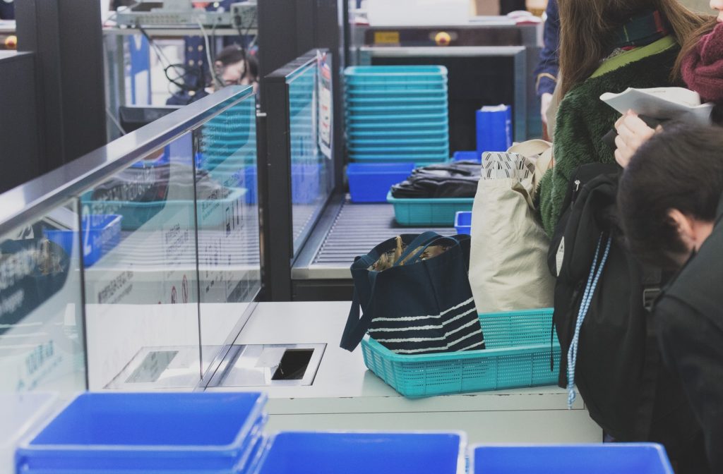 保安検査場でトレーに荷物を載せて並ぶ人たち