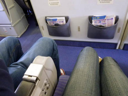 機内の座席に座った人の足元と前の座席の間隔