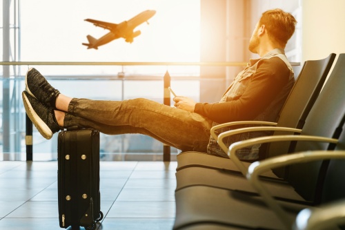 空港の待合室で足を伸ばして飛行機を見る男性