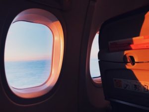 夕暮れの海を映す機内の丸い窓2つ