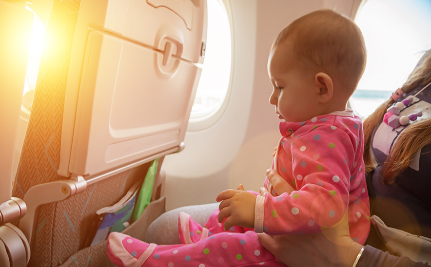 機窓のそばで座席に座る赤ちゃん