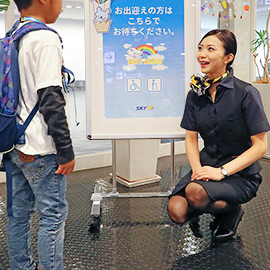 空港のカウンターで子どもと話す客室乗務員