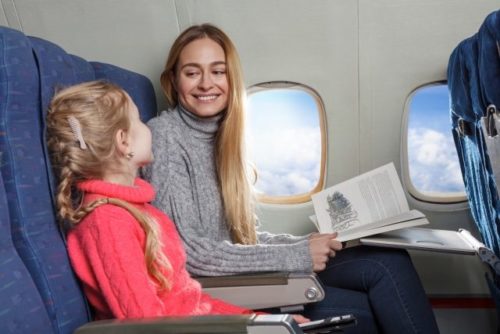 機内で女の子と本を読む女性
