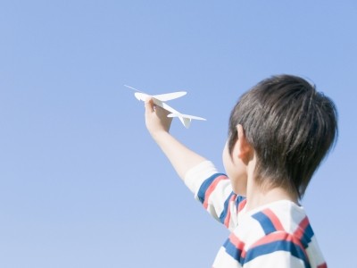 青空へ紙飛行機を飛ばす男の子