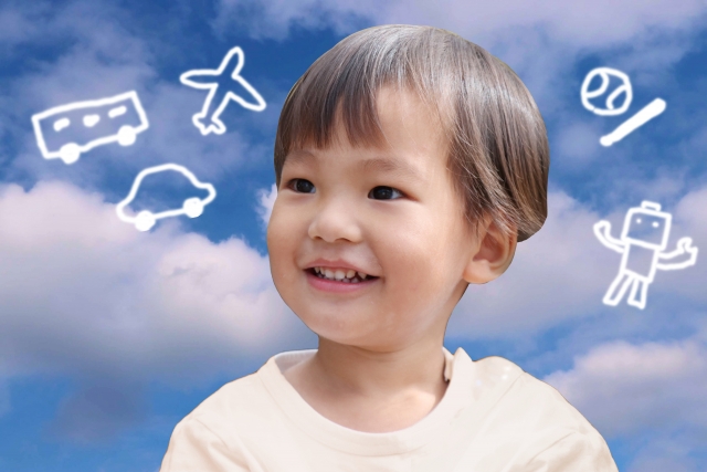 乗り物の絵に囲まれて笑う男の子